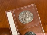 someone is holding two silver coins in their hand on a wooden table