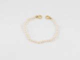 un bracelet de perles avec un fermoir en or sur fond blanc
