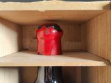 a red candle sitting in a black vase in a wooden box