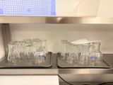 bottles and glasses are lined up on a shelf in a kitchen