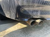 un gros plan sur le pot d'échappement d'une voiture garée sur le bord de la route
