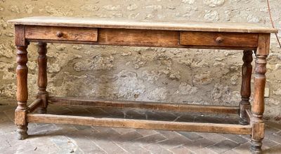 a wooden table with two drawers on it in front of a stone wall