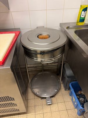 a trash can in the corner of a kitchen next to a sink