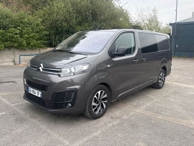 Une camionnette Citroën garée sur un parking, avec des arbres et des buissons en arrière-plan