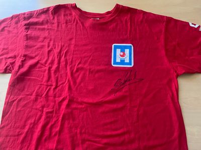 red t - shirt with blue and white sticker on it sitting on a table