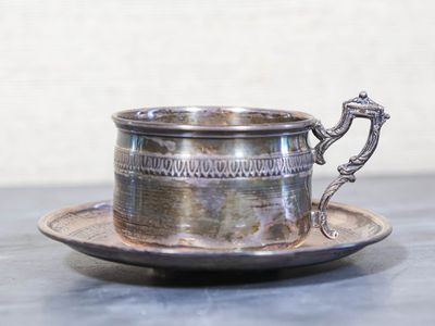 une tasse et une soucoupe en argent posées sur une table