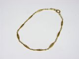 gros plan d'un bracelet en or sur une surface blanche
