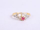 un gros plan d'une bague en or sertie d'une perle et d'un rubis