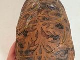 a person holding a brown vase with designs on it