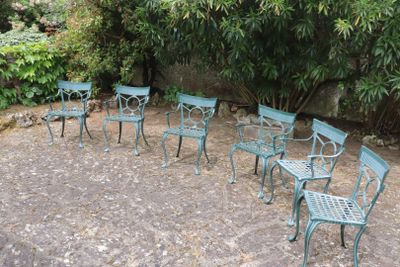 six chairs and a table in the middle of a garden