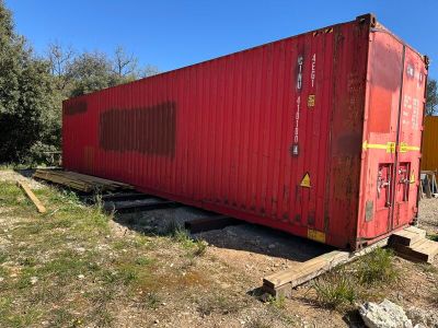 un conteneur d'expédition rouge posé au bord de la route