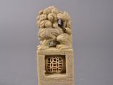 two carved ivory figurines of lions on top of a stone block