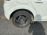 une petite voiture blanche avec un pneu crevé dans la rue