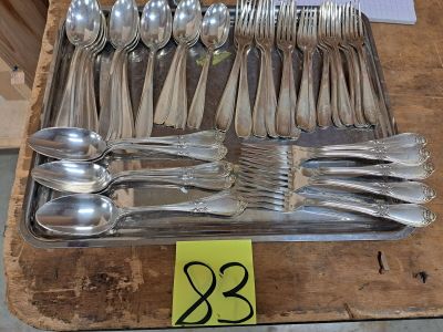 de nombreuses cuillères et cuillères à soupe disposées sur un plateau, accompagnées d'une étiquette de prix