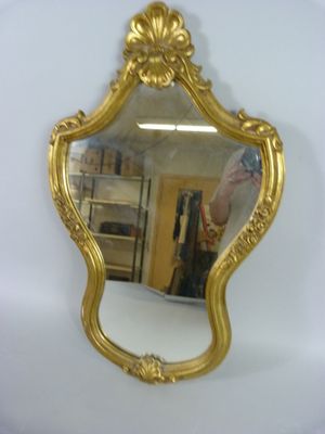 un miroir accroché au mur, avec un cadre doré