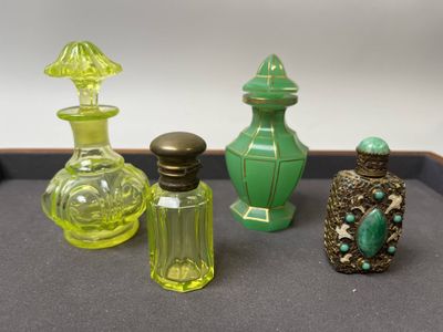 quatre bouteilles en verre de couleurs différentes posées sur un plateau