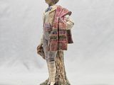 figurine of a boy with a hat and scarf standing on a tree stump