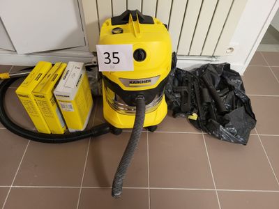 un aspirateur jaune posé par terre à côté d'un sac noir