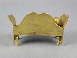 gold plated miniature bed with gold legs on a white surface