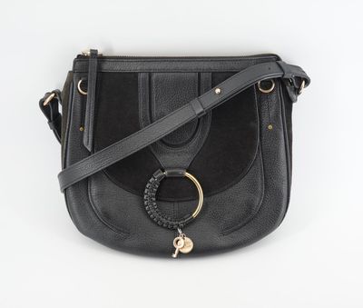 a black leather cross body bag with a metal ring on the front