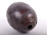 a brown ball with holes on it on a white surface