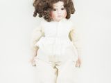 une image représentant une poupée aux cheveux bouclés et vêtue d'une robe blanche