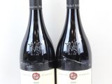 deux bouteilles de vin rouge posées l'une à côté de l'autre sur une surface blanche