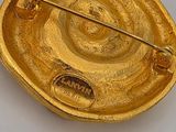 gold plated brooch with a pin in the middle of it