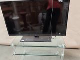 a glass tv stand with a laptop on top of it