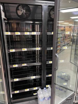 des bouteilles d'eau sont rangées dans une glacière dans une épicerie