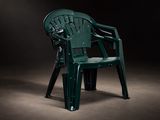 une chaise en plastique verte qui se trouve dans l'obscurité