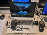 two laptops sitting on a desk with headphones and a mouse