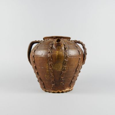 an old brown vase with handles on a white surface