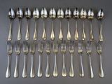 a lot of silver spoons and forks laid out on a table
