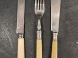 three forks and a knife on a table with a knife in the middle