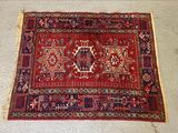 Le tapis posé au sol est rouge et bleu et comporte un motif.
