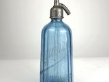 une bouteille en verre bleue munie d'une pompe métallique sur le dessus