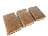 three old books sitting on top of each other on a white surface