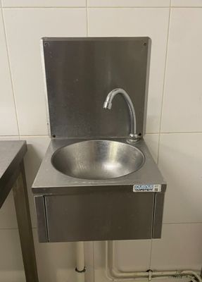 un lavabo en inox dans une salle de bains, équipé d'un robinet en métal