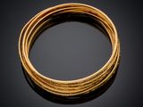 gros plan d'un bracelet en or sur une surface noire
