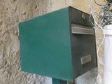 a green mail box sitting next to a white mail box