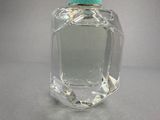 a clear glass bottle with a green lid on a table