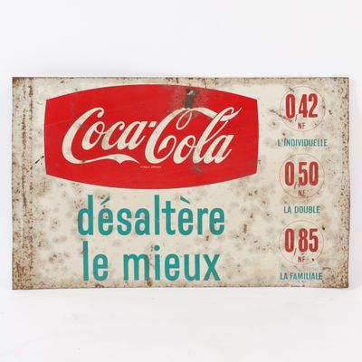 une vieille enseigne Coca-Cola sur fond blanc, avec une étiquette rouge et bleue