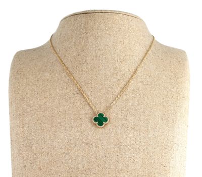 a gold necklace with a green clover pendant on a mannequin