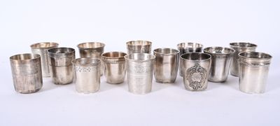 six tasses en argent et une cuillère en argent sont alignées sur une surface blanche