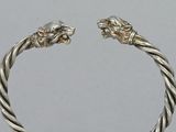 pair of silver bracelets with lion heads on them on a table