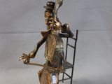 statue of a woman sitting on a chair holding a spoon and a spoon