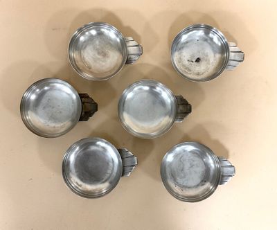 six théières en argent sont disposées en cercle sur une table