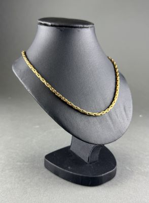 a black mannequin with a gold chain on it