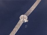 an image of a wrist watch with a silver band on a blue surface